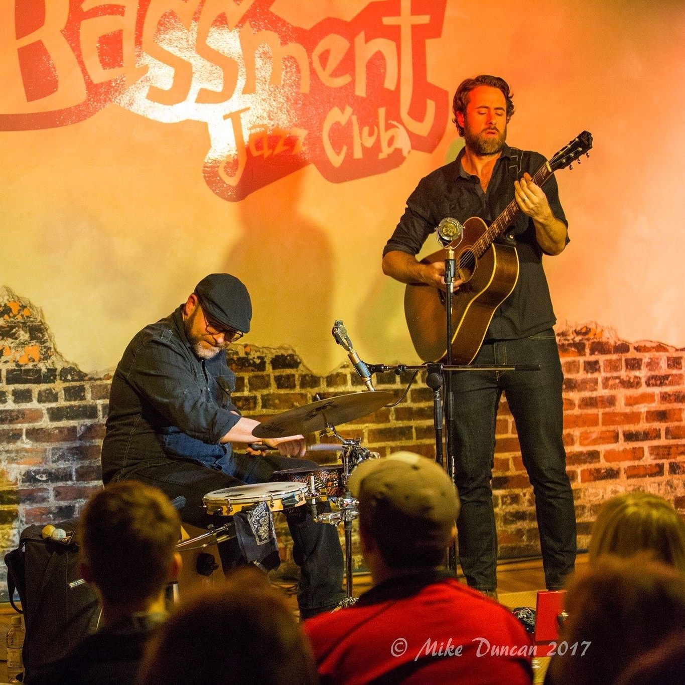 Two musicians playing live music on the drums and guitar